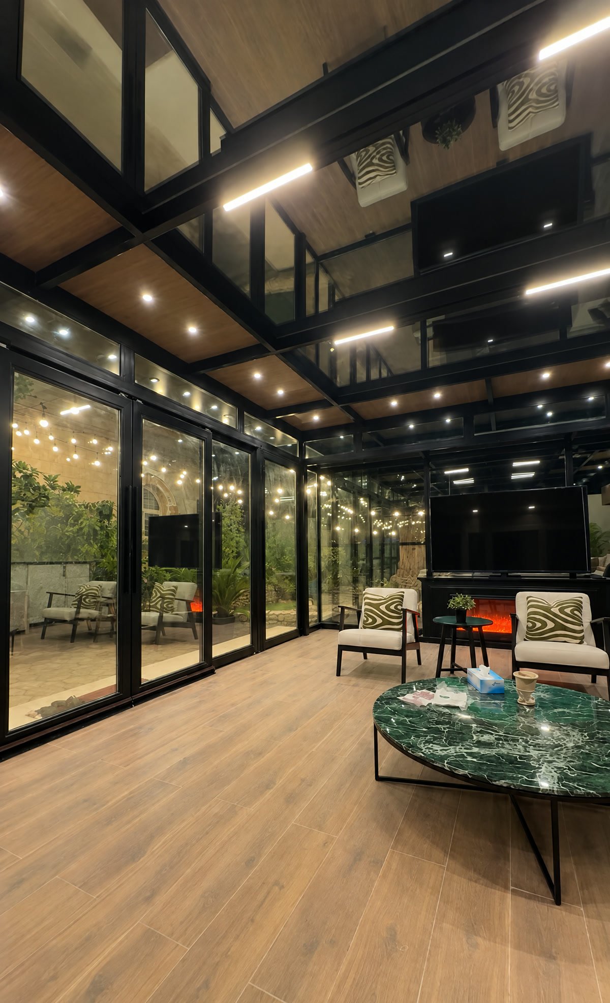 Tall glass room at night with a wood ceiling full of downlights